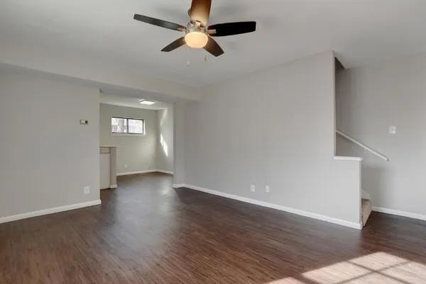 an empty room with wooden floor fan and windows