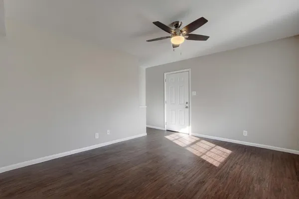 an empty room with wooden floor and ceiling fan