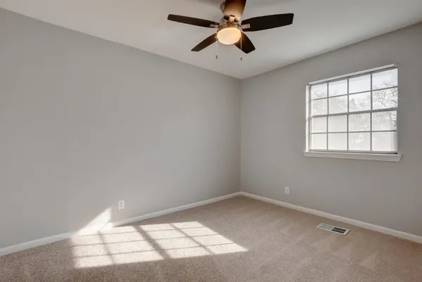 an empty room with a window and a fan