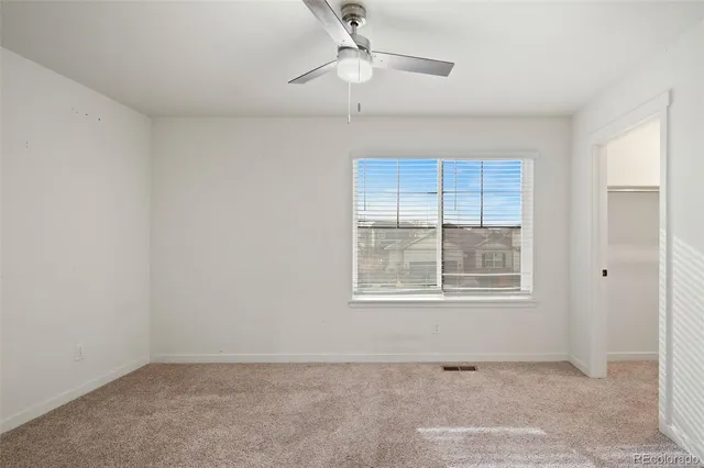 an empty room with closet and a chandelier fan