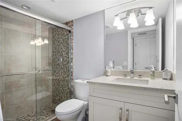 a bathroom with a sink vanity granite toilet and shower