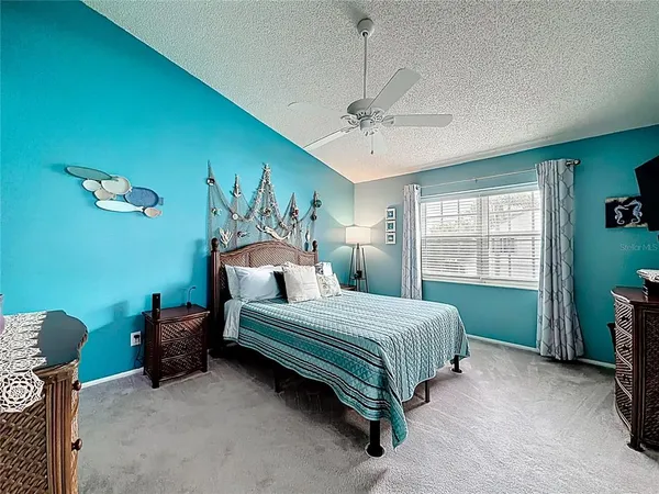 a bedroom with a bed a ceiling fan and a dresser
