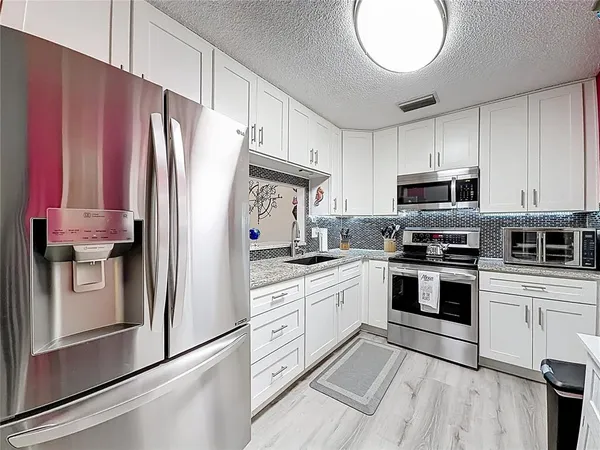 a kitchen with granite countertop a refrigerator stove and microwave