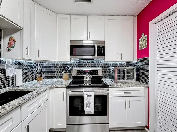 a kitchen with stainless steel appliances kitchen island granite countertop a refrigerator and microwave