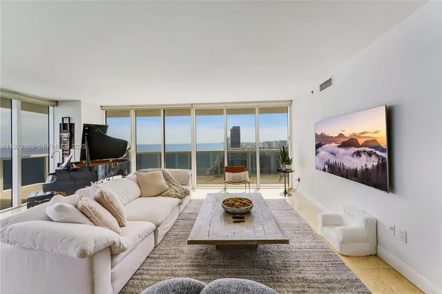 a living room with furniture floor to ceiling window and a flat screen tv