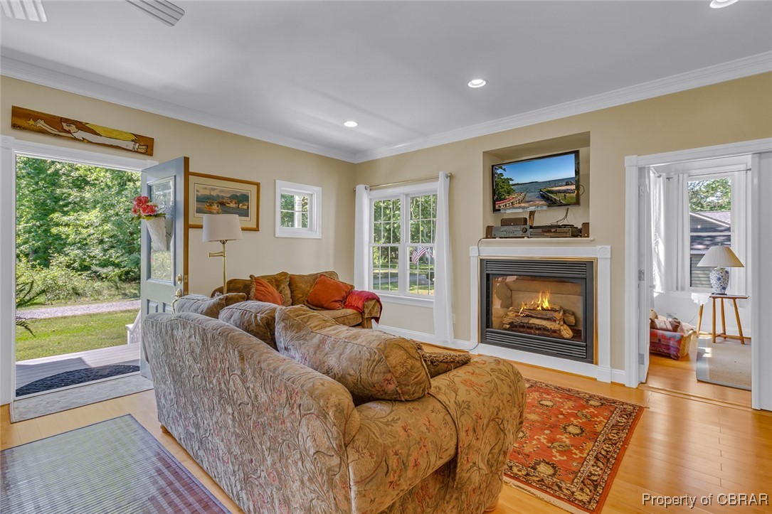 189 Virginia Road Reedville, VA 22539 - Photo 6 of 46 Living room with ornamental molding, wood finished floors, a lit fireplace, and recessed lighting