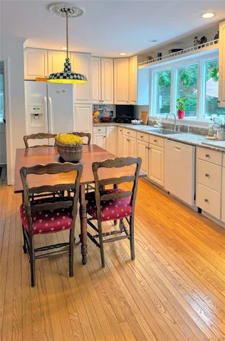 a kitchen with stainless steel appliances kitchen island granite countertop a stove a sink and white cabinets with wooden floor