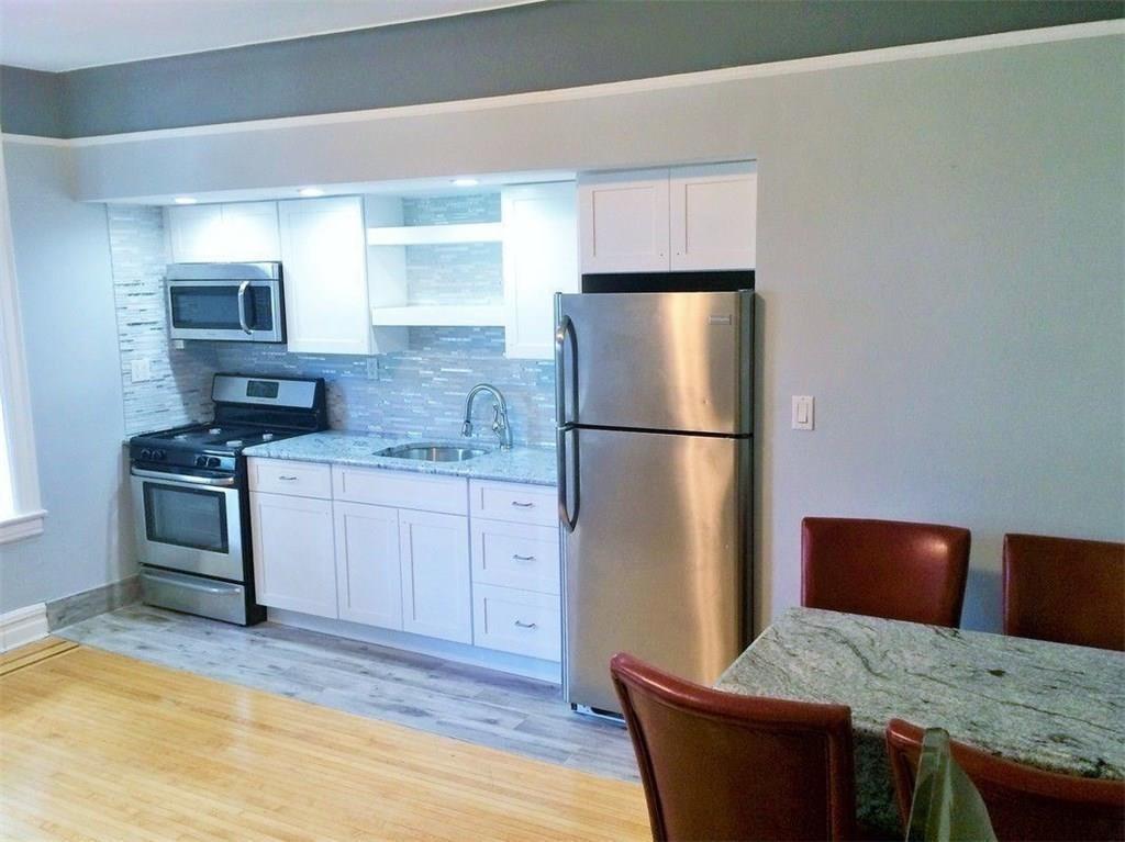 a kitchen with granite countertop a refrigerator and a stove top oven