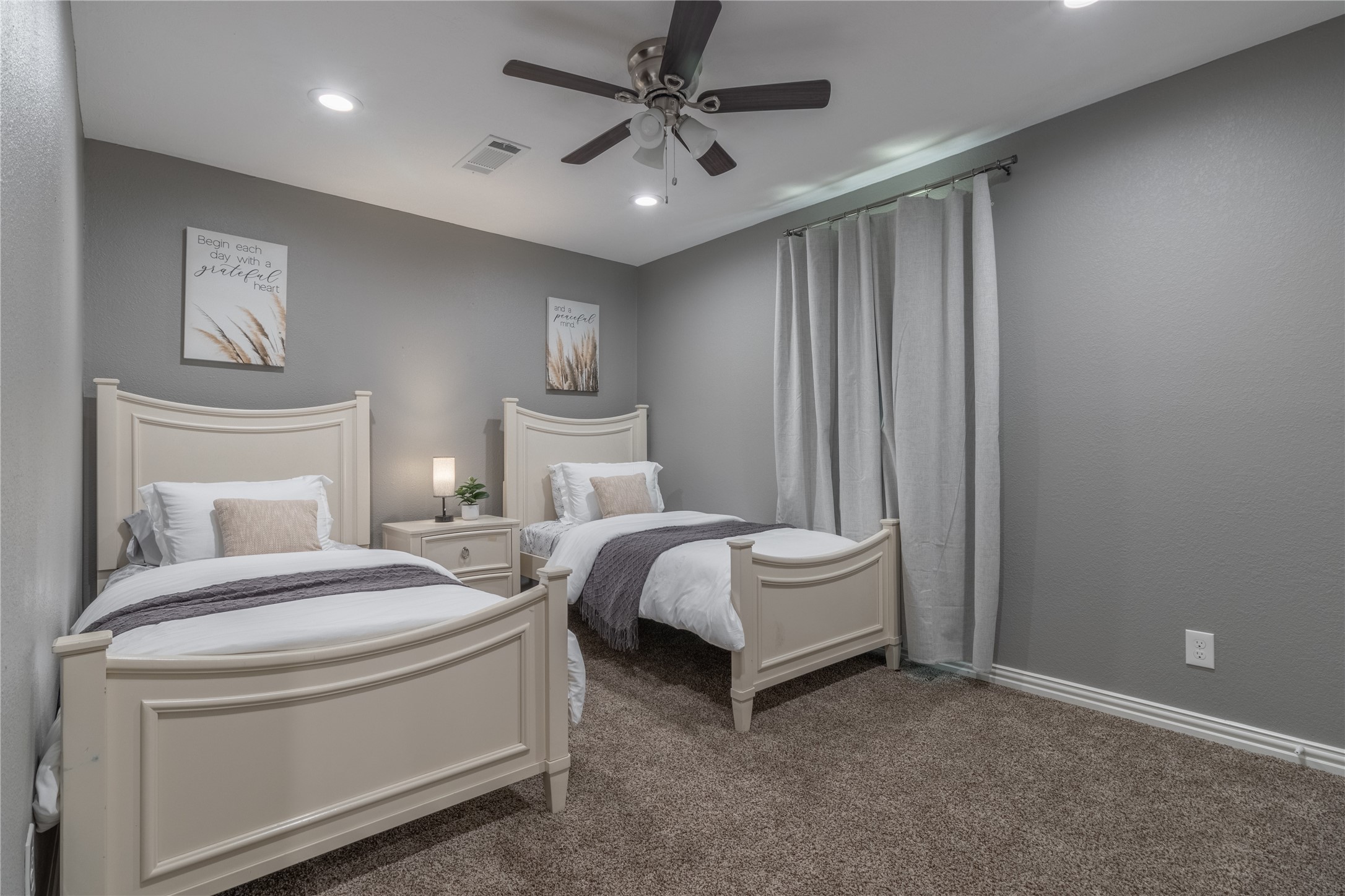 17123 Atlanta Street Humble, TX 77396 - Photo 17 of 29 This cozy bedroom features two twin beds with elegant headboards, neutral decor, and soft lighting. The room has plush carpeting, a ceiling fan, and simple wall art, creating a serene and welcoming atmosphere.