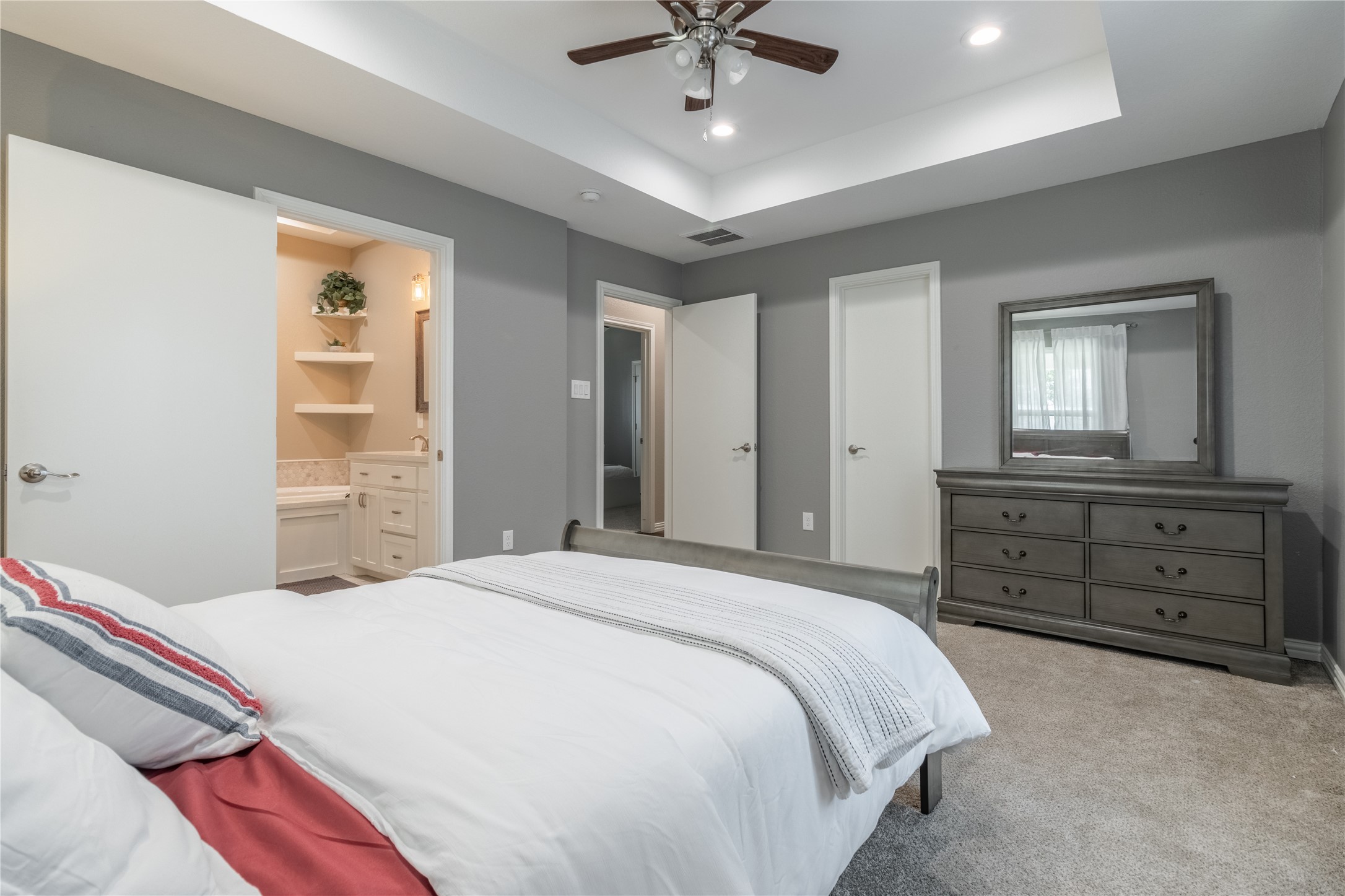 17123 Atlanta Street Humble, TX 77396 - Photo 20 of 29 This bedroom features a cozy atmosphere with soft gray walls, a ceiling fan, and recessed lighting. It includes a spacious ensuite bathroom, a large dresser with a mirror, and plush carpeting, offering both comfort and style.