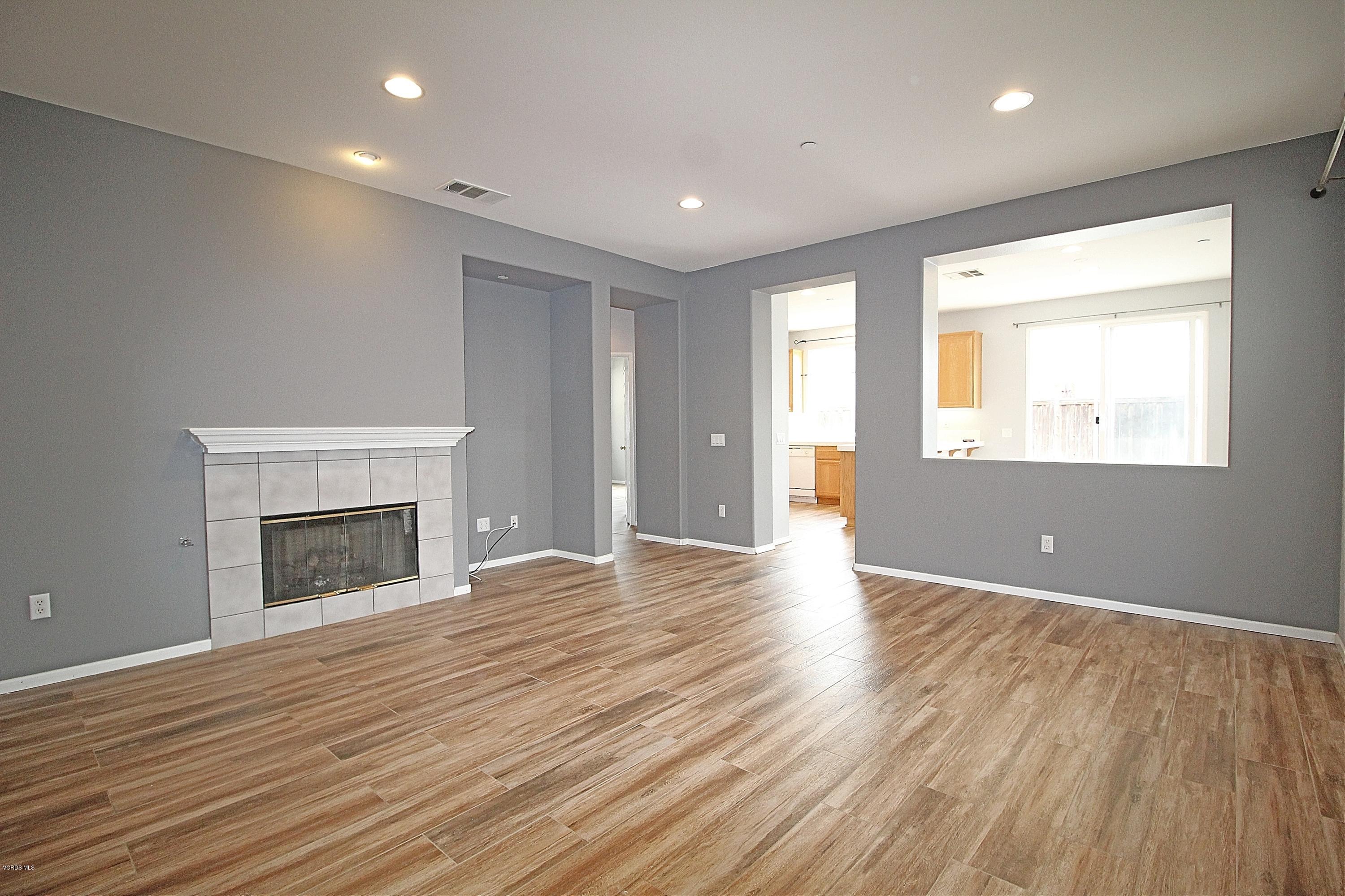 an empty room with wooden floor fireplace and windows
