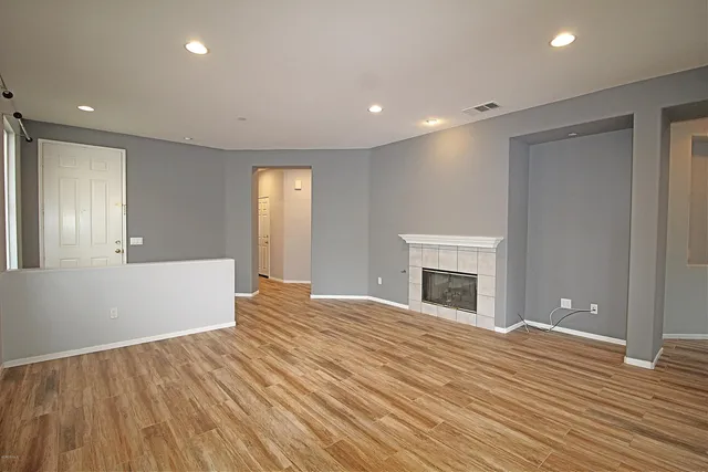 a view of an empty room with wooden floor and a fireplace