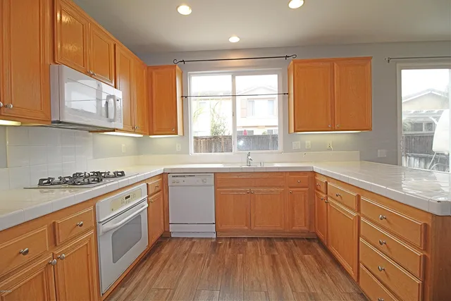 a kitchen with stainless steel appliances granite countertop a sink a stove cabinets and wooden floor