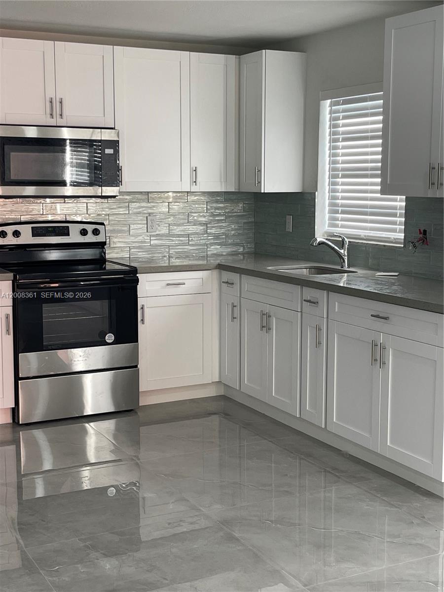 4281 Riverside Drive, Unit 3 Coral Springs, FL 33065 - Photo 5 of 8 a kitchen with granite countertop a stove a sink and a microwave