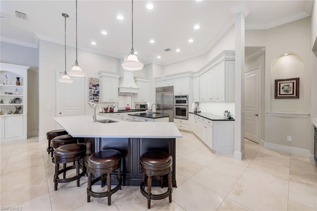 9243 Marble Stone Drive Naples, FL 34120 - Photo 10 of 50 a kitchen with kitchen island a dining table chairs sink and cabinets
