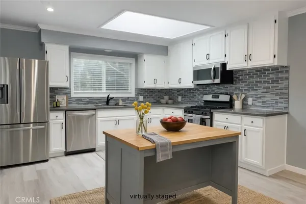 a kitchen with stainless steel appliances granite countertop a sink stove refrigerator and cabinets