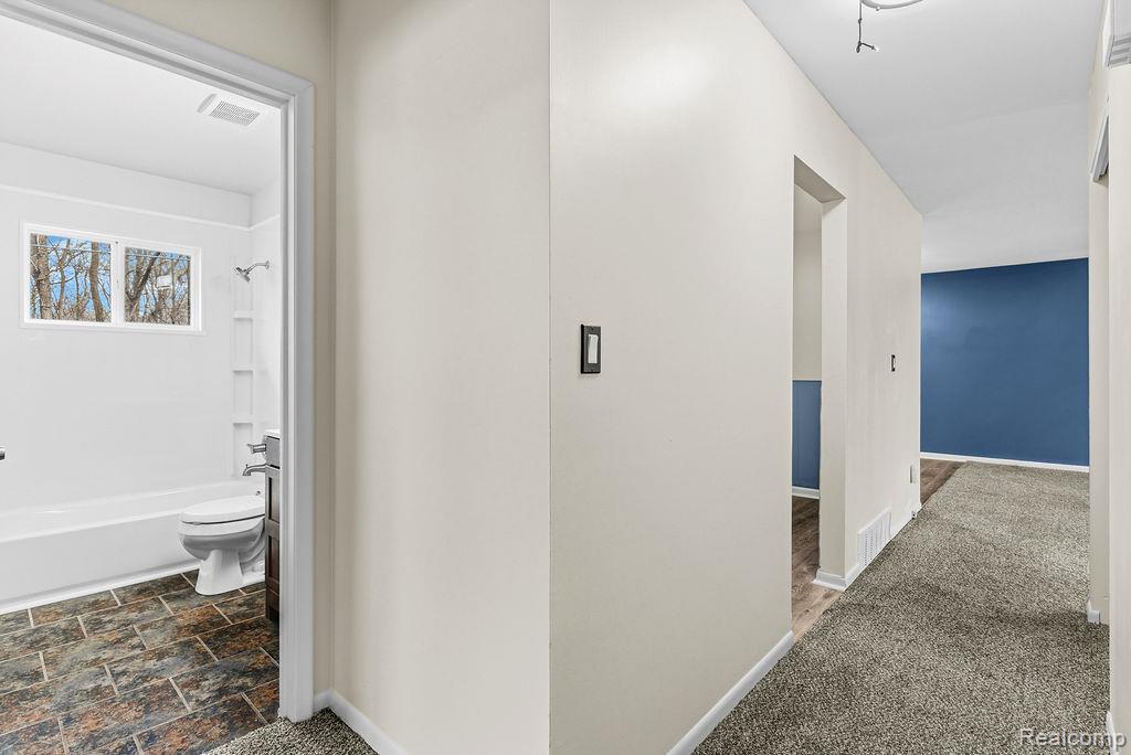 3485 Hammerberg Road Flint, MI 48507 - Photo 14 of 35 Corridor featuring dark colored carpet and dark stone finish flooring