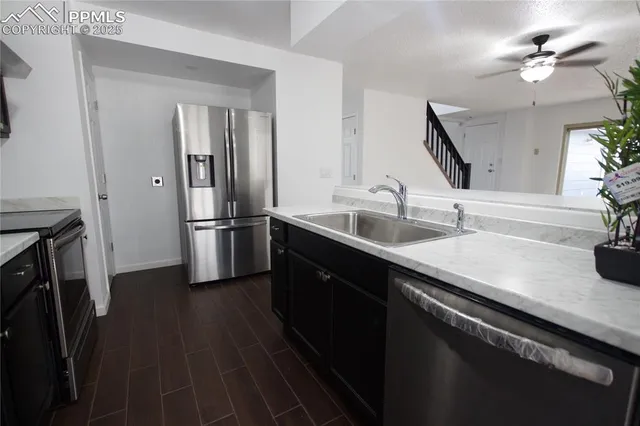 a kitchen with stainless steel appliances a sink dishwasher a refrigerator and a stove with wooden floor