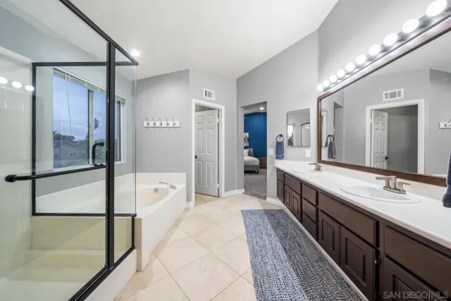 a spacious bathroom with a double vanity sink a large mirror of shower