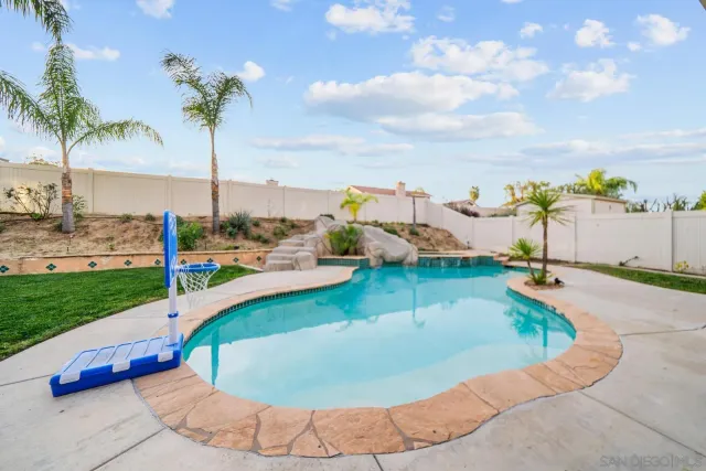 a view of a swimming pool with a yard and palm trees