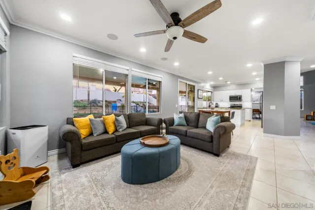 a living room with furniture kitchen view and a chandelier