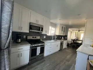 a kitchen with white cabinets and appliances