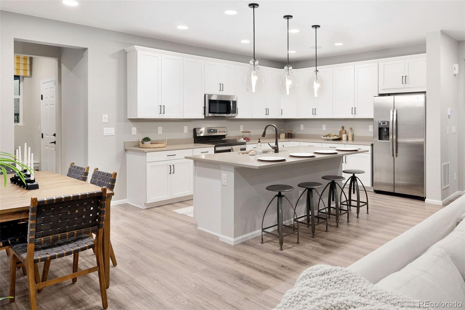 3957 Breakcamp Court Castle Rock, CO 80108 - Photo 19 of 50 a large kitchen with kitchen island a dining table chairs and white cabinets