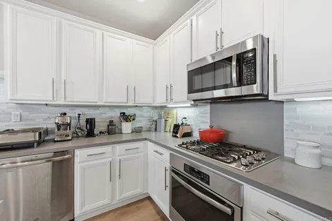 a kitchen with stainless steel appliances granite countertop white cabinets a stove top oven and dishwasher