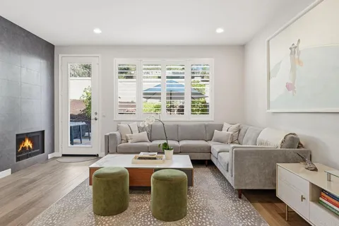 a living room with furniture a fireplace and a floor to ceiling window