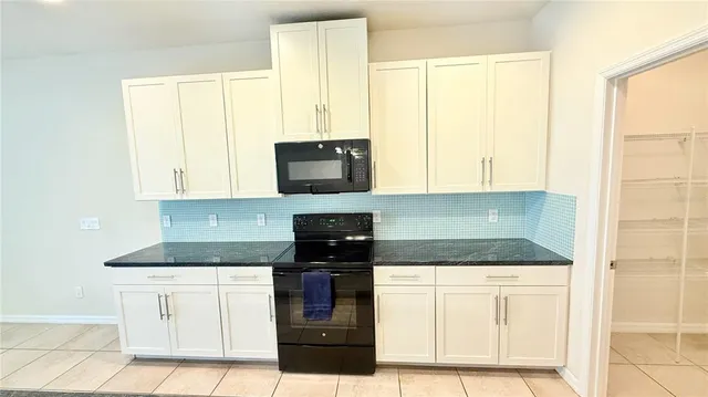 a kitchen with granite countertop white cabinets and black appliances
