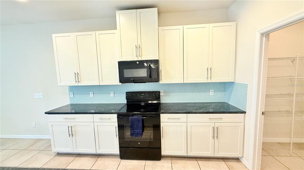 7580 Aloma Pines Court Winter Park, FL 32792 - Photo 8 of 36 a kitchen with granite countertop white cabinets and black appliances