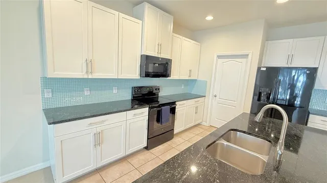 a kitchen with granite countertop a sink a counter top space stainless steel appliances and cabinets