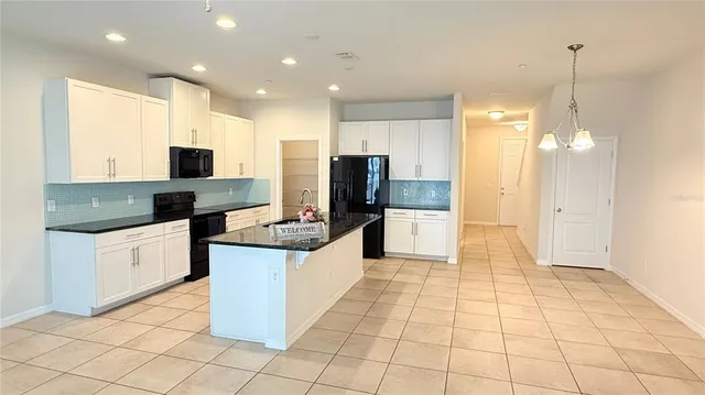 a large kitchen with stainless steel appliances kitchen island granite countertop a refrigerator and a stove top oven