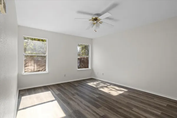 a view of empty room with wooden floor and fan