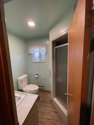 a view of an empty room with wooden floor and a ceiling fan