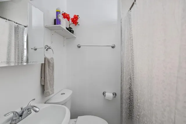 a bathroom with a toilet sink and shower curtain