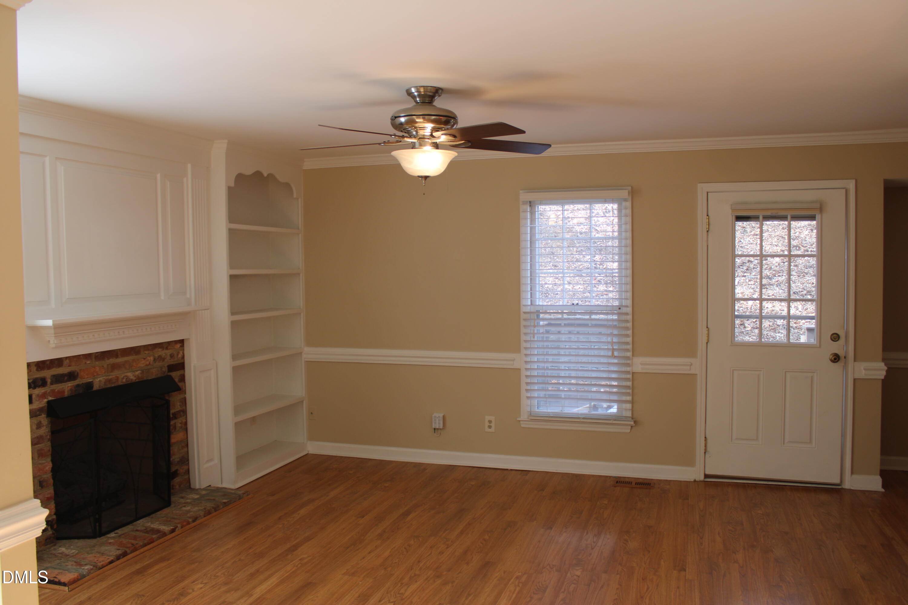 6701 Queen Annes Drive Raleigh, NC 27613 - Photo 11 of 23 an empty room with wooden floor fireplace and windows