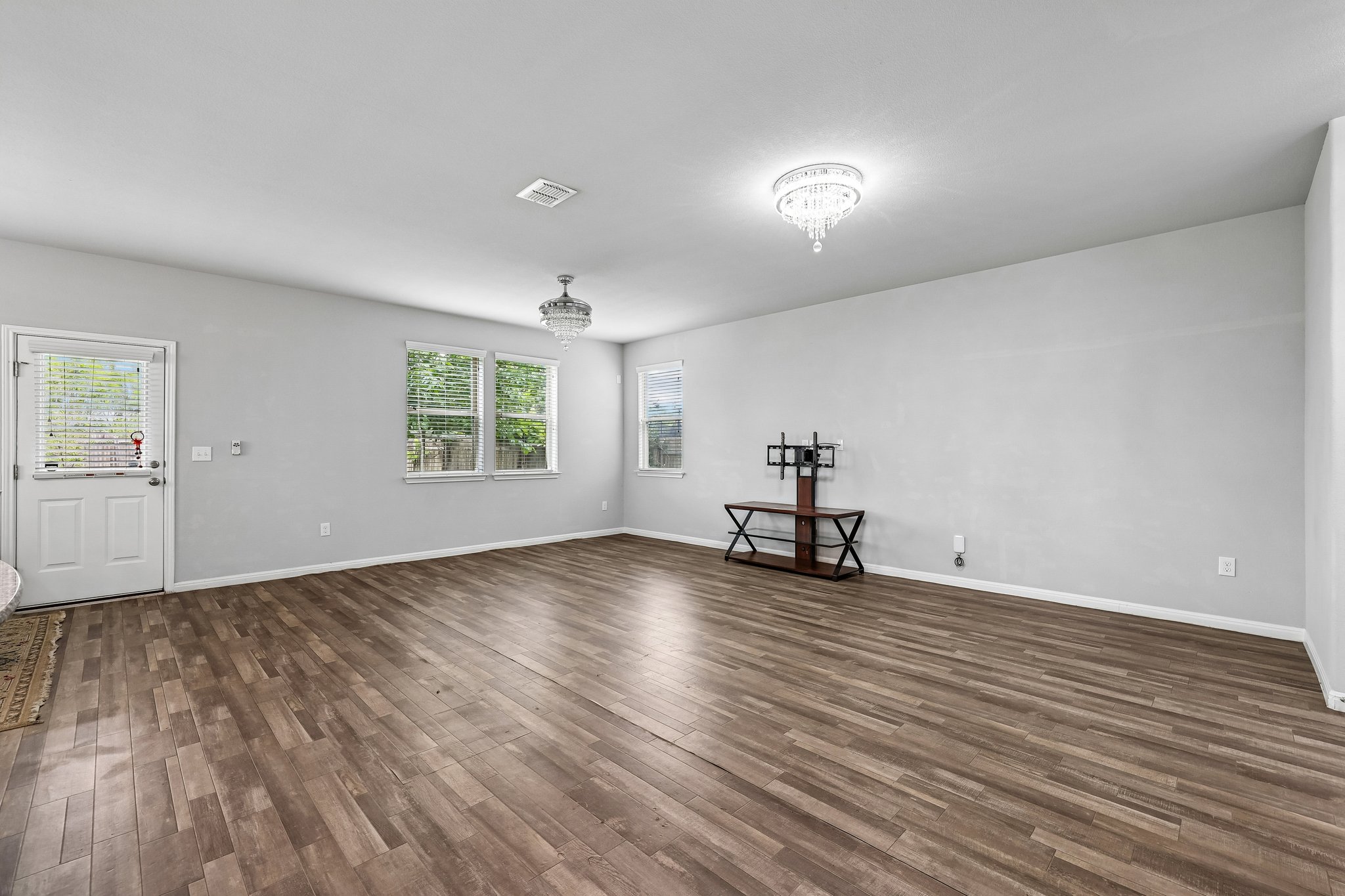387 Guemal Road Buda, TX 78610 - Photo 7 of 39 Spacious room featuring wood-finish flooring, light gray wall paint, and white trim