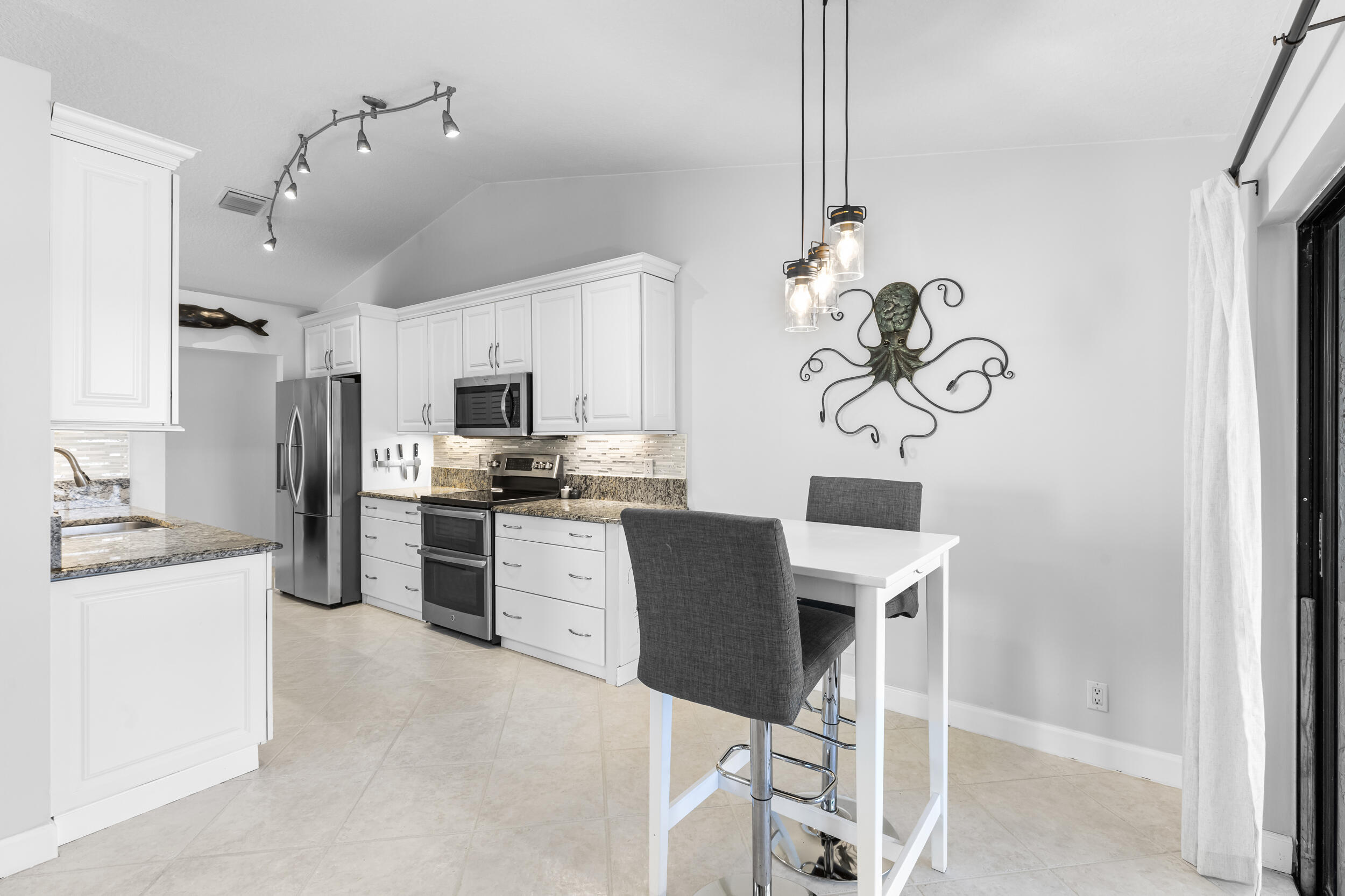 14451 Parker Ridge Court Delray Beach, FL 33484 - Photo 13 of 48 a kitchen with a refrigerator a stove top oven a sink dishwasher and a dining table with wooden floor