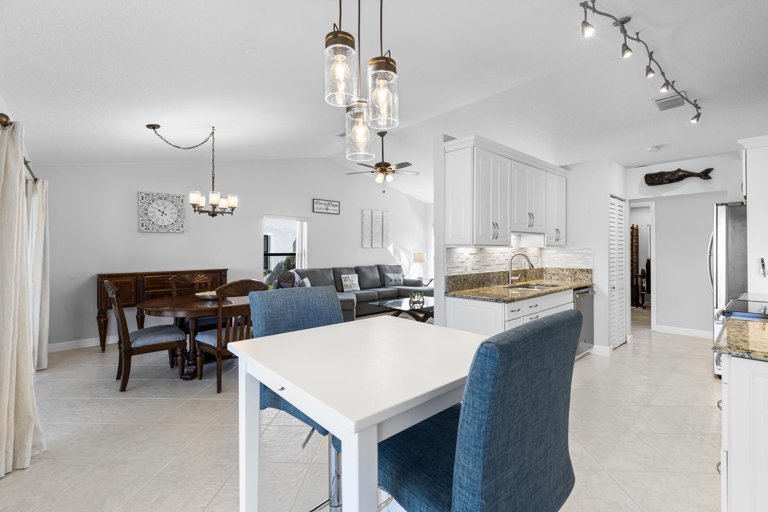14451 Parker Ridge Court Delray Beach, FL 33484 - Photo 15 of 48 a living room with stainless steel appliances kitchen island a table chairs and chandelier