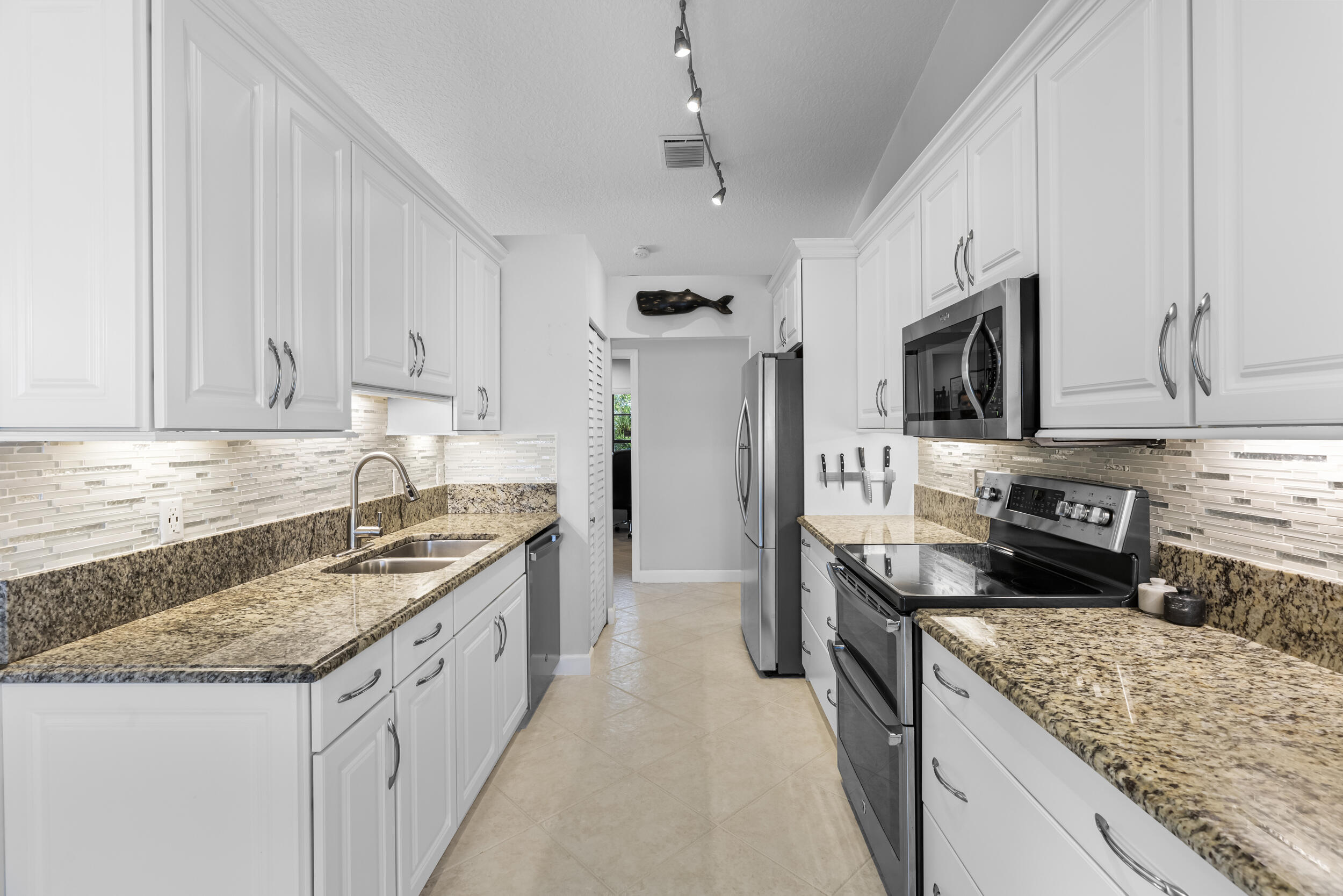 14451 Parker Ridge Court Delray Beach, FL 33484 - Photo 17 of 48 a kitchen with granite countertop a sink stove and refrigerator