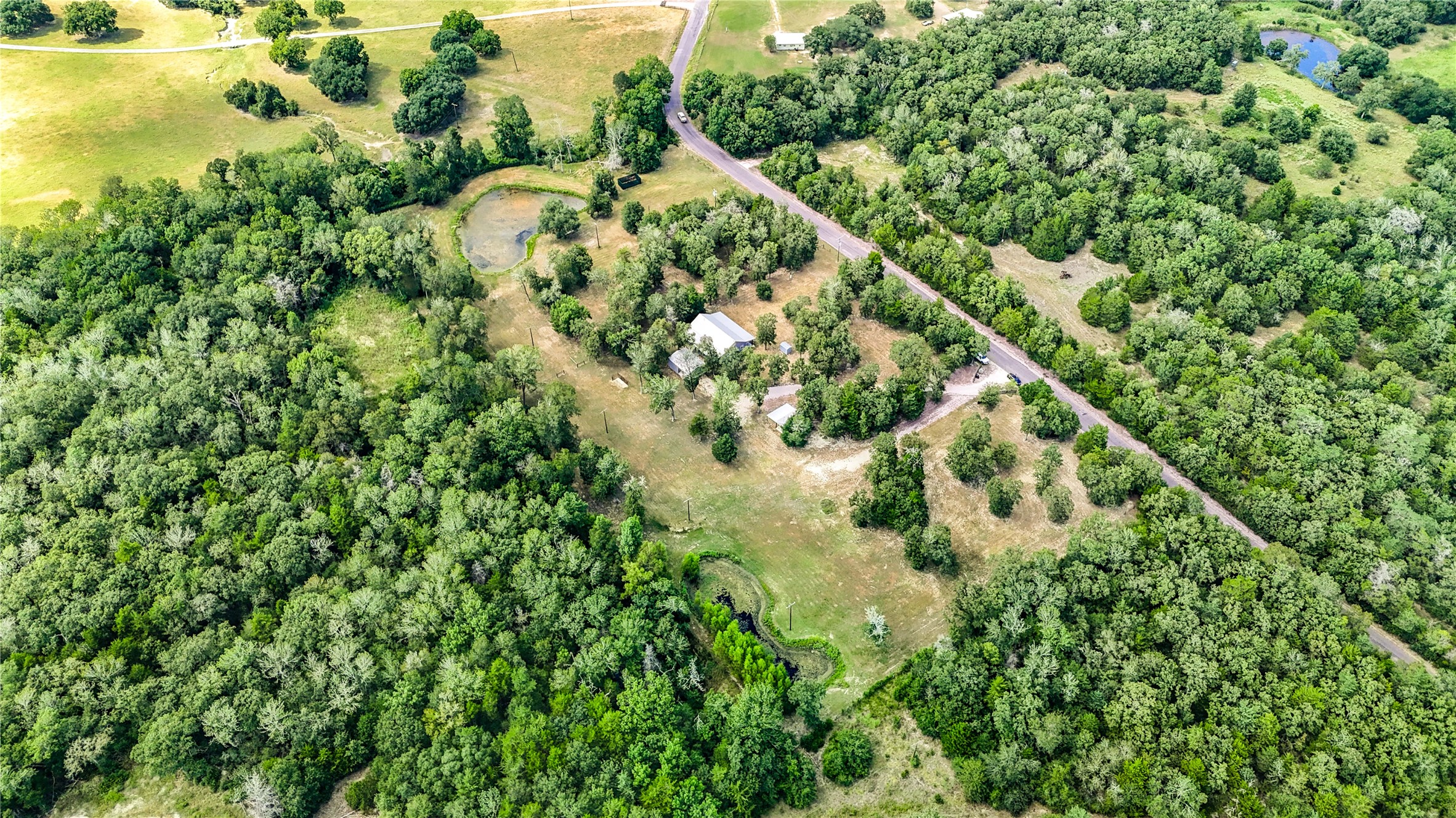 8805 Sun Oil Road Brenham, TX 77833 - Photo 45 of 50 Expansive rural property nestled in lush greenery, featuring a private road and serene surroundings perfect for tranquility and privacy.