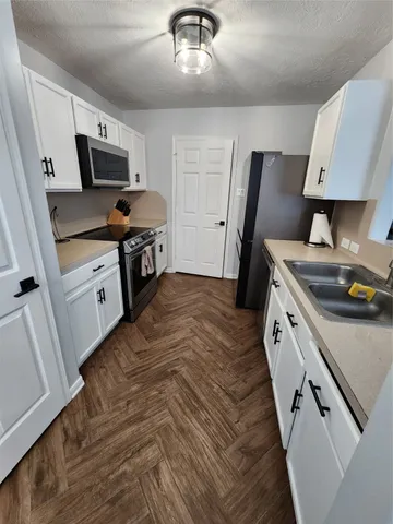 a kitchen with granite countertop a sink stainless steel appliances and white cabinets