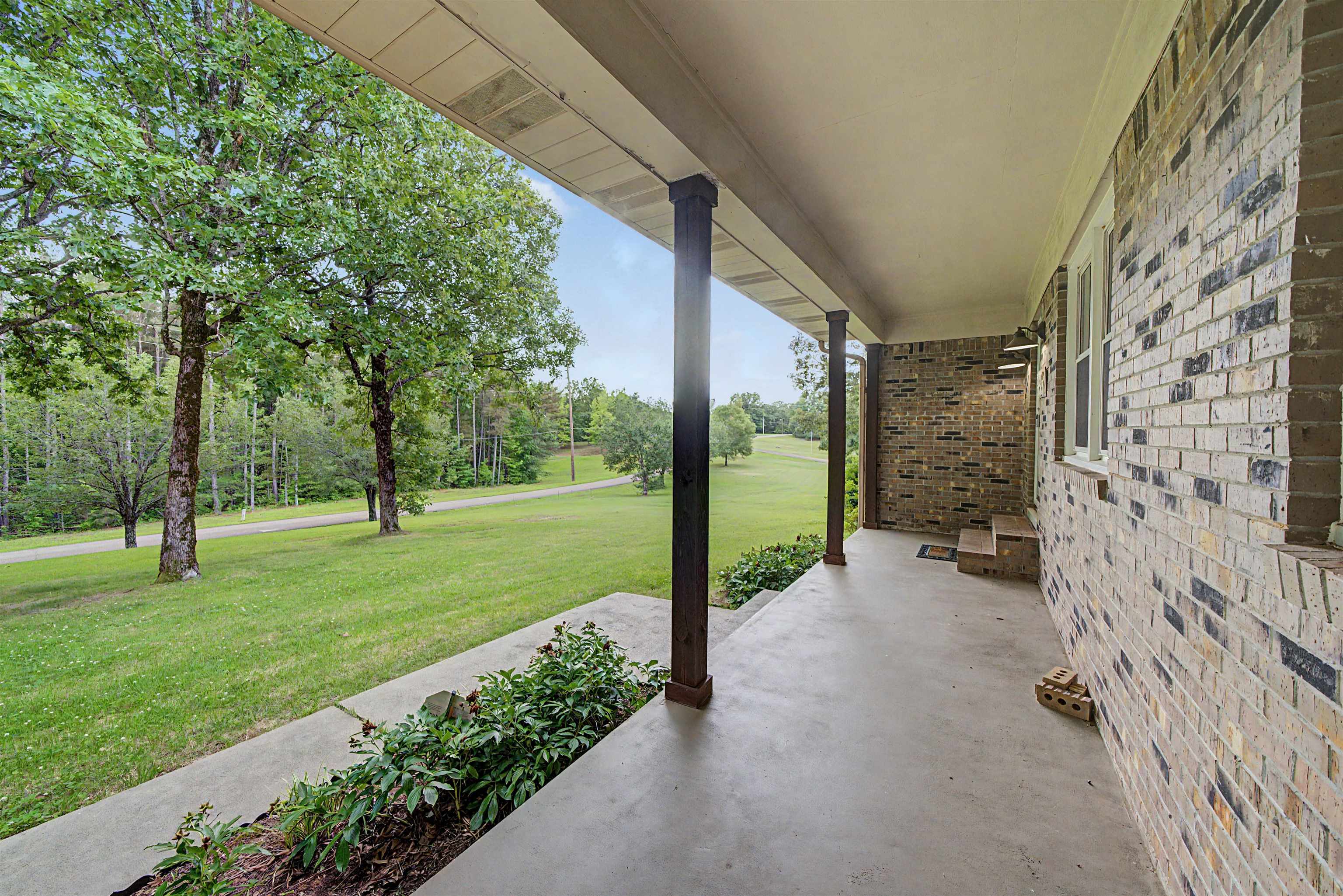 436 Skyline Road Selmer, TN 38375 - Photo 9 of 40 Covered porch featuring brick exterior, concrete flooring, and dark support columns