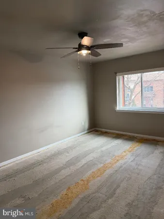 an empty room with windows and ceiling fan