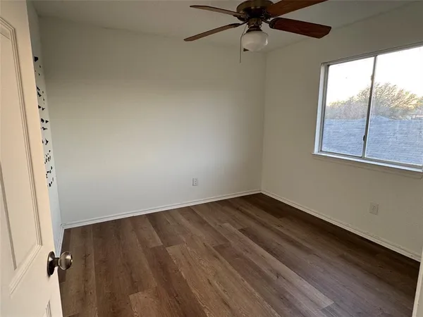 an empty room with a window and ceiling fan