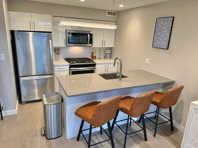 a kitchen with stainless steel appliances a refrigerator a stove a sink and a dining table