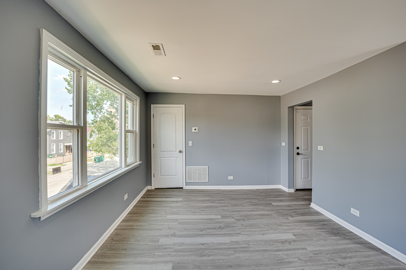 208 Mound Street, Unit 2 Joliet, IL 60433 - Photo 5 of 18 a view of an empty room with wooden floor and a window