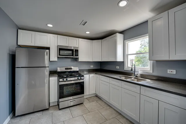 a kitchen with kitchen island granite countertop stainless steel appliances a stove a sink a microwave and cabinets