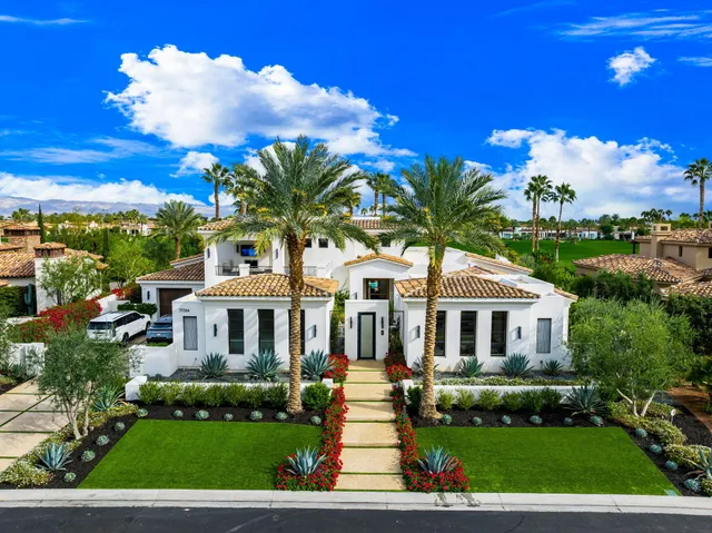 a front view of a house with a yard and potted plants